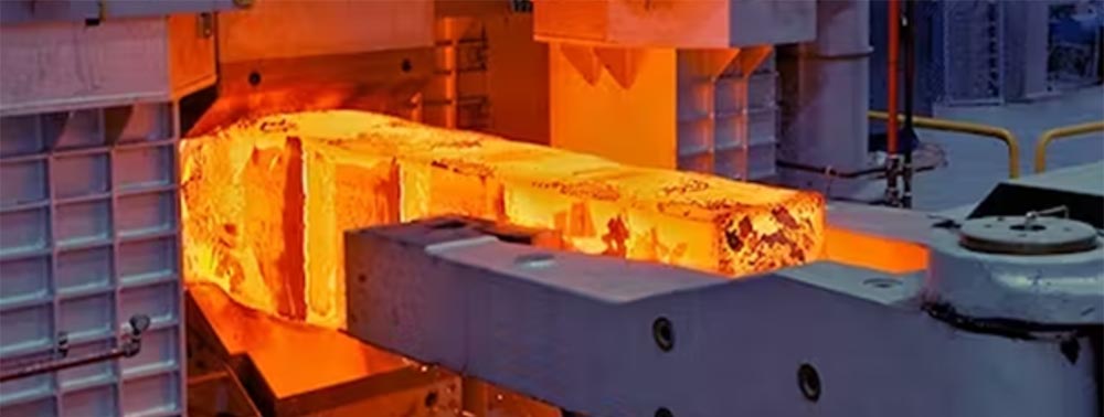 A molten hot high-strength precision forging is pulled from a large furnace.