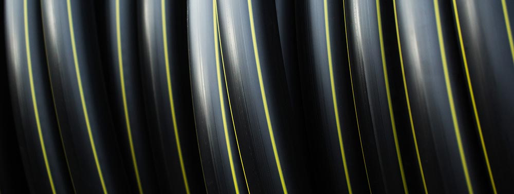 A black high-quality hose with yellow trim is rolled and stacked.